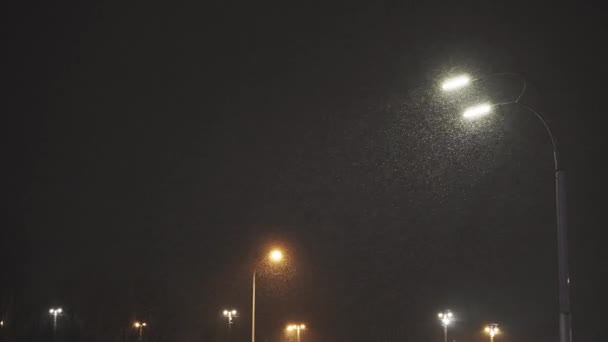 Pouliční světlo zářící v tmavé zimní noci. Městská lucerna v padajícím sněhu na Štědrý večer. Pouliční lampa v padajícím sněhu v zimním městě — Stock video