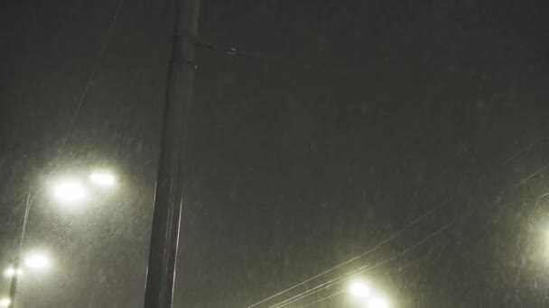 Luz de rua brilhando na noite escura de inverno. Lanterna da cidade em queda de neve na noite de Natal. Lâmpada de rua em queda de neve na cidade de inverno — Vídeo de Stock