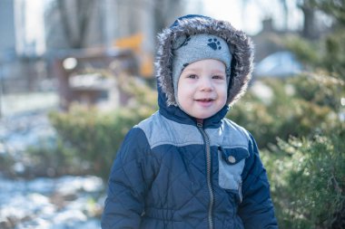 Kışın ardıç çalılarının arkasında saklambaç oynayan bir çocuk.