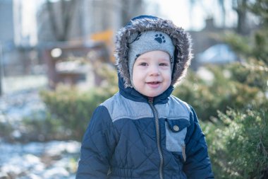 Kışın ardıç çalılarının arkasında saklambaç oynayan bir çocuk.