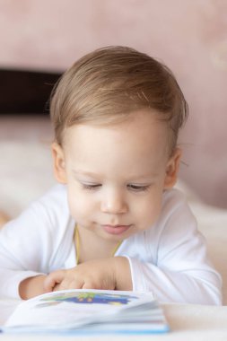 Sevgili çocuklar, erkek ve kız kardeşler, yatakta kitap okuyorlar. Yataktaki çocukları kitap okurken çek. Beyazlı bir kız ve erkek yatakta oynuyorlar. Yatakta beyazlı bebekler var. Tatlı çocuklar..