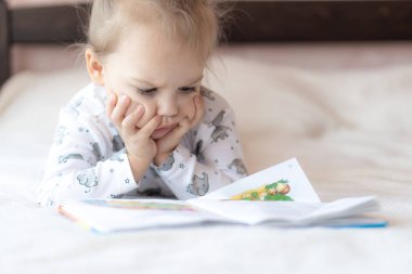 Sevgili çocuklar, erkek ve kız kardeşler, yatakta kitap okuyorlar. Yataktaki çocukları kitap okurken çek. Beyazlı bir kız ve erkek yatakta oynuyorlar. Yatakta beyazlı bebekler var. Tatlı çocuklar..
