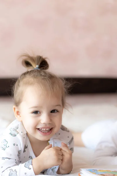 Schöne Kinder - Bruder und Schwester, die ein Buch lesen, auf dem Bett. Großaufnahme von Kindern, die im Bett ein Buch lesen. Ein Junge und ein Mädchen in Weiß spielen auf dem Bett. Babys in Weiß auf dem Bett. Niedliche Kinder. — Stockfoto