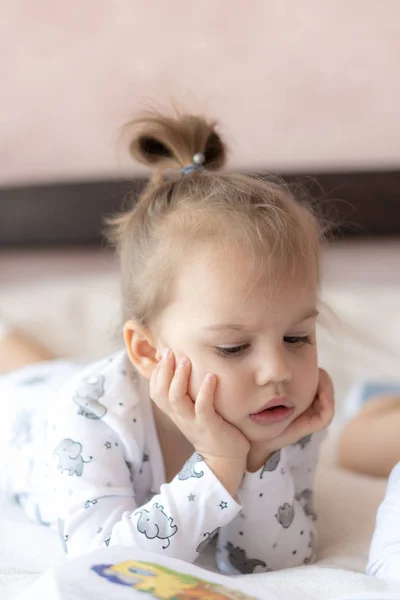 Bambini adorabili - fratello e sorella, leggendo un libro, sul letto. Primo piano dei bambini a letto che leggono un libro. Un ragazzo e una ragazza in bianco stanno giocando sul letto. Bambini in bianco sul letto. Bambini carini.. — Foto Stock