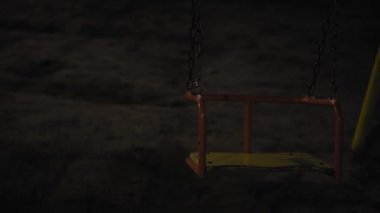 Geceleri çocuk parkında sallan, parkta kimse olmasın. Karanlıkta yakın çekimler. Salıncak yavaşça sallanıyor. Geceleri terk edilmiş oyun parkı. Parktaki kasvetli gece manzarası.