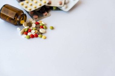 Medicine and pills. Multi-colored medicines on a white background close-up. Brown glass bucket and tablets with pills on a white background. Multi-colored tablets that spilled from an inverted jar