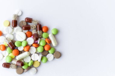 Medicines and pills. Multicolored medicines on a white background close-up. A slide of colored tablets on a white background. Multi-colored tablets that spilled from an inverted jar onto a white