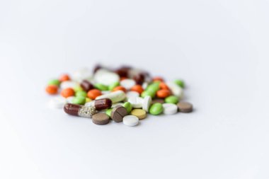 Medicines and pills. Multicolored medicines on a white background close-up. A slide of colored tablets on a white background. Multi-colored tablets that spilled from an inverted jar onto a white