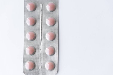 Medicines and pills. Multicolored medicines on a white background close-up. Plate with pink pills on a white background. Multi-colored tablets that spilled from an inverted jar onto a white surface.