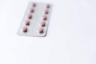 Medicines and pills. Multicolored medicines on a white background close-up. Plate with pink pills on a white background. Multi-colored tablets that spilled from an inverted jar onto a white surface.