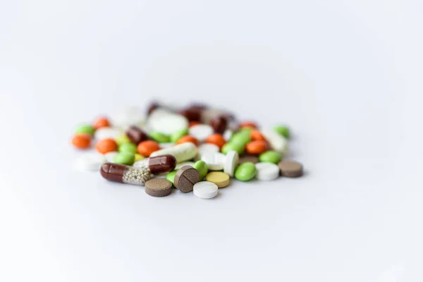 Medicines and pills. Multicolored medicines on a white background close-up. A slide of colored tablets on a white background. Multi-colored tablets that spilled from an inverted jar onto a white — Stock Photo, Image