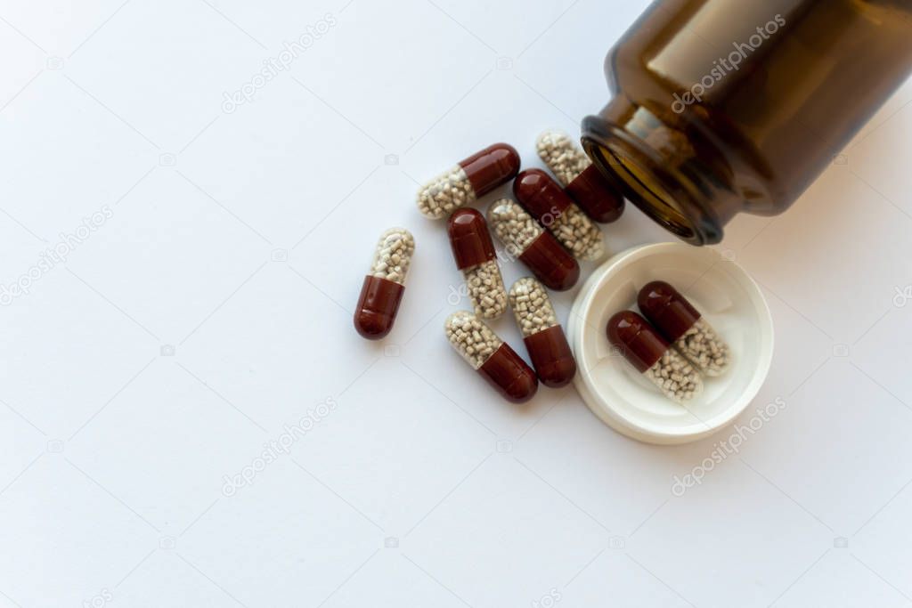 Medicine and pills. Medicines on a white background close-up. Brown glass bucket with capsules inside on a white background. Pills that spilled out of an inverted jar onto a white surface.