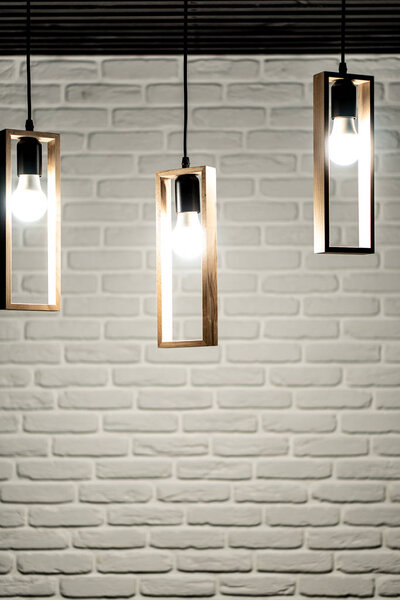 Три лампы на фоне белой кирпичной стены. Три лампочки на белом кирпичном фоне. Белый кирпичный фон с тремя вихрями, которые висят сверху
.