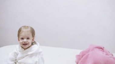 Banyo yaptıktan sonra ıslak saçlı, beyaz arka planda iki çocuk. Beyaz bir yatakta duştan sonra kız ve erkek. Bornozlu kız ve erkek kardeşler yatmadan önce oynarlar. Çocuklar, İrlandalı ikizler