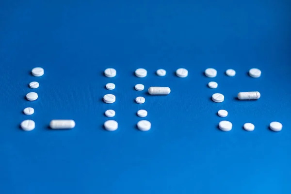 The word life made up of white pills and capsules on a classic blue background. White tablets and capsules laid out in the form of the word life. Word written in white pills on a blue background. — Stock Photo, Image