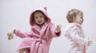 Banyo yaptıktan sonra ıslak saçlı, beyaz arka planda iki çocuk. Beyaz bir yatakta duştan sonra kız ve erkek. Bornozlu kız ve erkek kardeşler yatmadan önce oynarlar. Çocuklar, İrlandalı ikizler