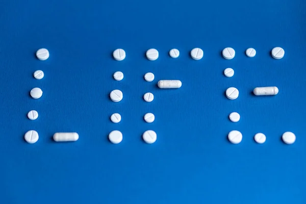 The word life made up of white pills and capsules on a classic blue background. White tablets and capsules laid out in the form of the word life. Word written in white pills on a blue background. — Stock Photo, Image