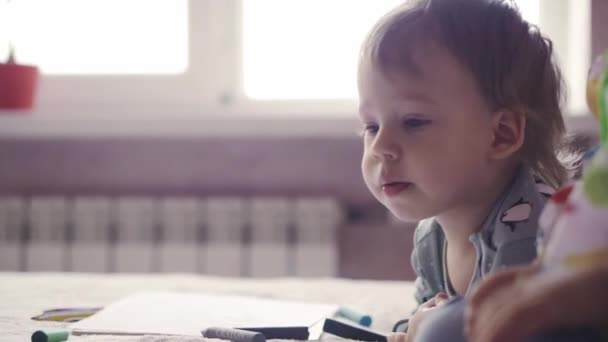 Twee schattige kinderen tekenen met idioten op het bed. Meisje en jongen spelen op het bed met potloden. Broer en zus tweeling tekenen met potloden terwijl ze op hun buik liggen. — Stockvideo