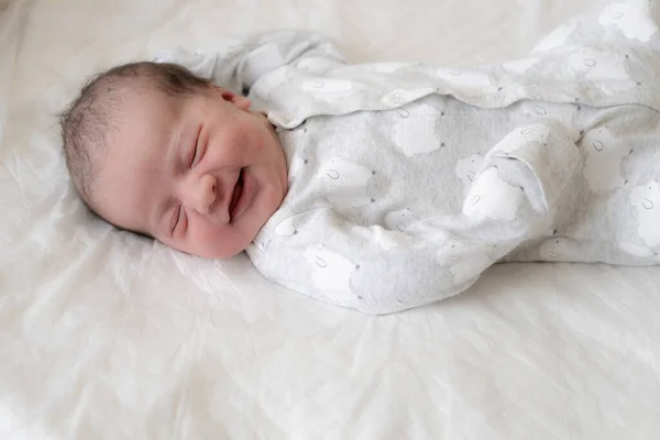 Retrato de um bebê recém-nascido nos primeiros minutos de vida, que sorri através de um sonho. Bebê recém-nascido sorri através de um sonho em um fundo branco . — Fotografia de Stock