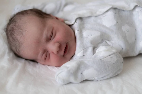 Retrato de um bebê recém-nascido nos primeiros minutos de vida, que sorri através de um sonho. Bebê recém-nascido sorri através de um sonho em um fundo branco . — Fotografia de Stock