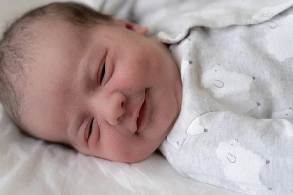 Retrato de um bebê recém-nascido nos primeiros minutos de vida, que sorri através de um sonho. Bebê recém-nascido sorri através de um sonho em um fundo branco . — Fotografia de Stock