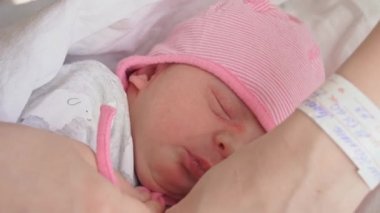 Yakın plan kadın elleri yeni doğmuş bir bebeğin şapkasını çıkarır. Annem yeni doğan bebeğin şapkasını çıkarır..