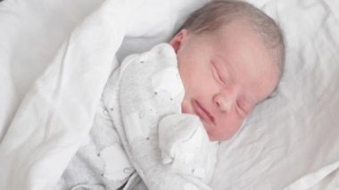 Yeni doğmuş bir bebek beyaz arka plandaki bir rüyada ellerini hareket ettirir. Şapkasız yeni doğmuş bebek beyaz bir arka planda uyur..