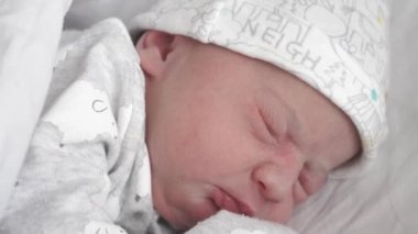 Yeni doğmuş bir bebeğin yakın plan yüzü. Uyanıp hayatının ilk günlerinde gözlerini açıyor. Yeni doğmuş bir bebek gözlerini açıyor..