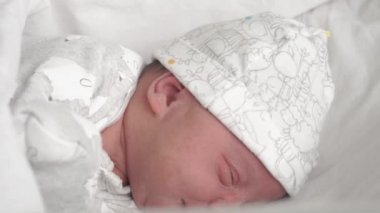 Yeni doğmuş bir bebeğin, yeni doğanlar için yapılmış camdan bir yatakta ağlayarak ve surat asarak yakın plan fotoğrafı. Yeni doğmuş bir bebek bir rüyada yüzünü buruşturur. Hayatın ilk dakikalarında yenidoğan.