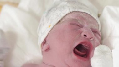 İlkel bir yağda ağlayan bir bebeğin portresini yakından çek. Gözleri açık, yeni doğmuş bir bebeğin yüzü, dengeli bir atış değil. Bebek doğduktan sonra ağlar, hayatın ilk dakikalarında..