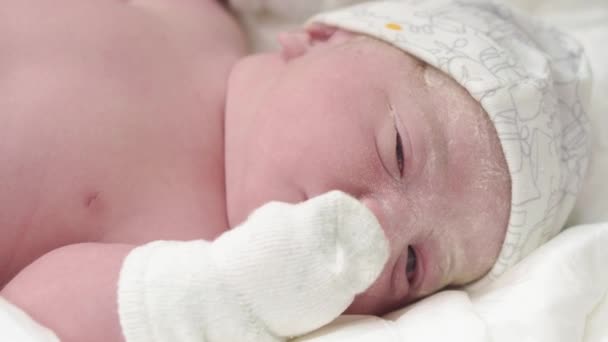 Ett närbild av ett gråtande nyfött barn i ett ursprungligt fett som öppnar ögonen och sticker ut tungan. Ansiktet på en nyfödd med öppna ögon närbild, inte stabiliserad skytte. — Stockvideo