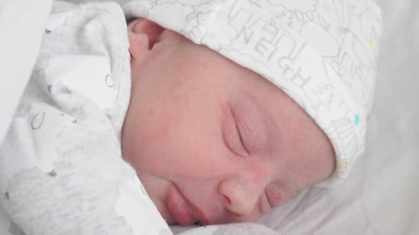 Close-up gezicht van een pasgeboren baby in de eerste dagen van het leven die op zoek is naar borsten door de slaap. Een pasgeboren baby grimt door een droom. — Stockvideo