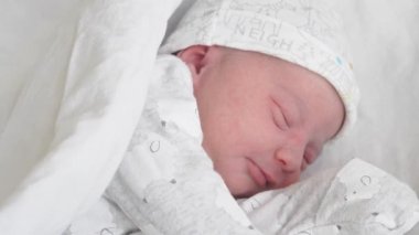 Yaşamın ilk günlerinde titreyen, gülümseyen ve bir rüyada esneyen yeni doğmuş bir bebeğin yüzünü yakından çek. Yeni doğmuş bir bebek bir rüyada yüzünü buruşturur. Hayatın ilk dakikalarında yeni doğmuş bir bebek.