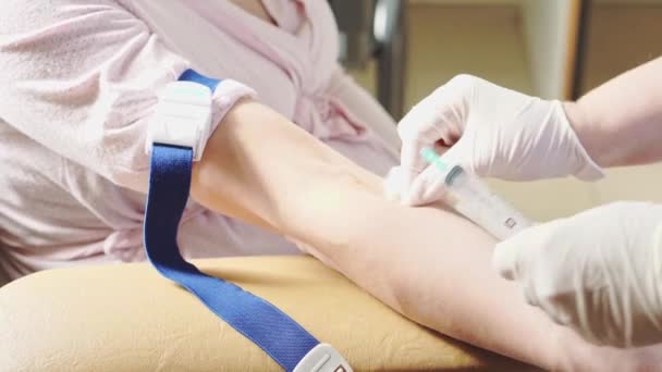 Enfermeira coleta de sangue da veia paciente que deitado na cama médica na clínica, mulher a ser testado close-up . — Vídeo de Stock
