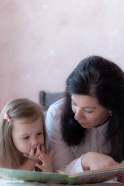 Büyükannem ve torunum yatakta kitap okuyorlar. Uzaktan öğrenme sırasında torunları olan büyükannesi yatakta. Büyükannem karantina sırasında torunlarıyla yatakta oynuyor..