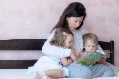 Büyükannem ve torunum yatakta kitap okuyorlar. Uzaktan öğrenme sırasında torunları olan büyükannesi yatakta. Büyükannem karantina sırasında torunlarıyla yatakta oynuyor..