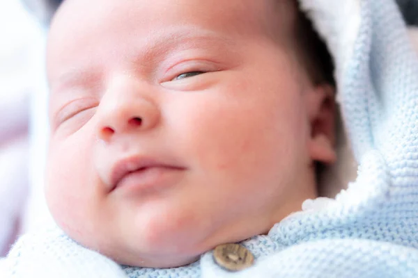 一个新生婴儿的近照。用睁开眼睛的新生儿的近视脸。一个新生儿正在近距离观察镜头.穿着蓝色上衣的新生儿. — 图库照片