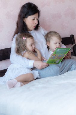 Büyükannem ve torunum yatakta kitap okuyorlar. Uzaktan öğrenme sırasında torunları olan büyükannesi yatakta. Büyükannem karantina sırasında torunlarıyla yatakta oynuyor..
