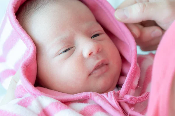 Annenin kollarında yeni doğmuş bir bebek. Yeni doğmuş bir bebeğin portresi. Yeni doğan bebeğin gözleri açık yakın plan yüzü. Bebek lense yakından bakıyor. Pembe bluzlu yeni doğmuş bebek.. — Stok fotoğraf