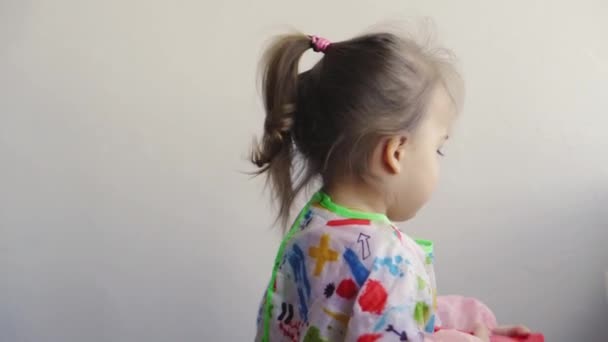 Repair, renovation, home, family, childhood, parenthood, fatherhood, self-isolation, quarantine concept - close-up little 3 years old girl playing with roller, painting wall in apartment white paint. — Stock Video