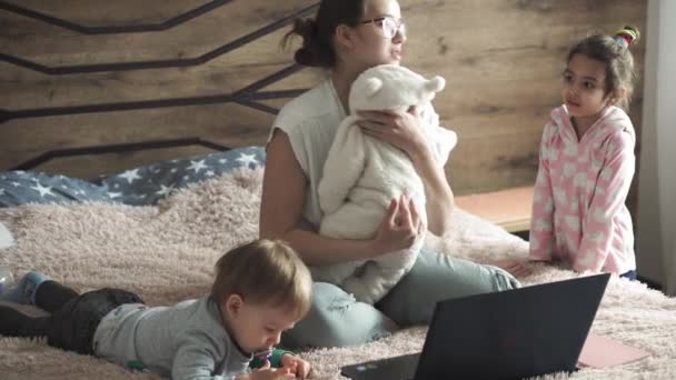 母亲、大家庭、超级母亲、童年、家庭、远程工作、自我隔离、技术概念- -带着幼儿躺在床上的年轻母亲，带着笔记本电脑、电话、平板电脑、笔记本、笔记本 — 图库视频影像
