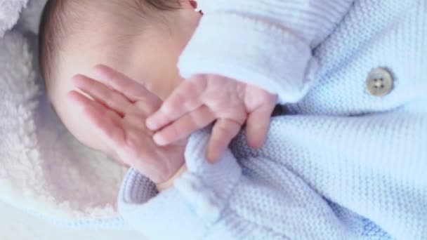 Baby, kindertijd, verzorging, kinderen concept - close-up portret van een pasgeboren baby slapen wakker liggen op zijn rug in een blauwe blouse met een kap op een beige achtergrond op het bed, bovenaanzicht. — Stockvideo