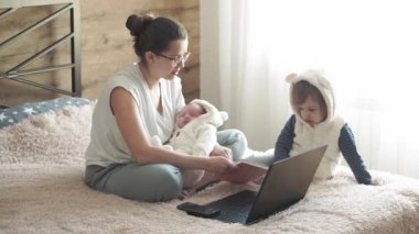 annelik, büyük aileler, süper anne, çocukluk, aile, tele çalışma, kendini izole etme, evde çalışma, teknoloji, konsept - yeni doğmuş bir anne ve küçük kızı dizüstü bilgisayarla yatakta, telefonla.