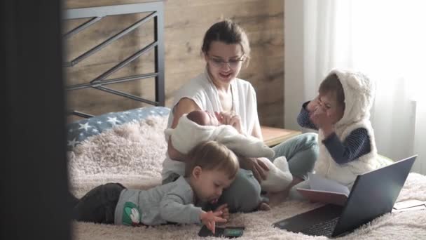 Maternidade, famílias grandes, super mãe, infância, família, teletrabalho, auto-isolamento, conceito de tecnologia - Mãe grande jovem com crianças pequenas na cama com laptop, telefone, tablet, bloco de notas, notebook — Vídeo de Stock