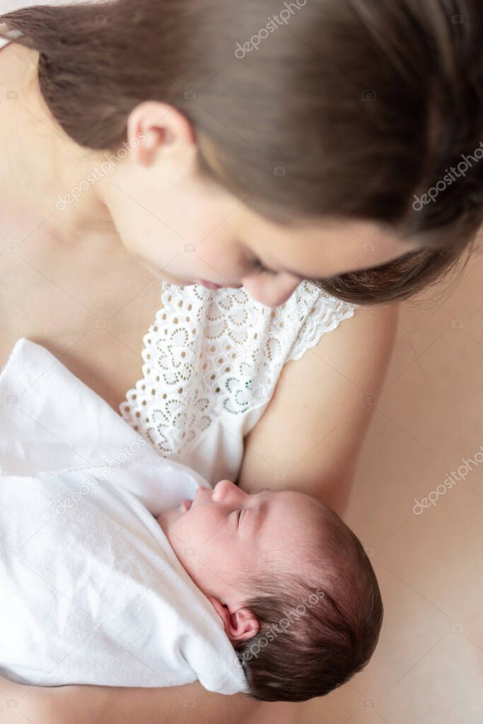motherhood, infancy, childhood, family, care, medicine, sleep, health, maternity concept - portrait of mom with newborn baby wrapped in diaper on white background, place for text, close-up, soft focus