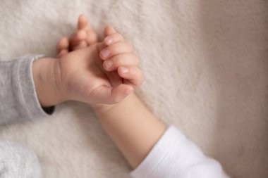 Çocukluk, uyku, rahatlama, aile, yaşam tarzı konsepti - 2 ve 3 yaşlarındaki iki genç, beyaz ve bej giysiler içinde öğle yemeğinde el ele tutuşarak bej ve beyaz bir yatakta uyurlar..