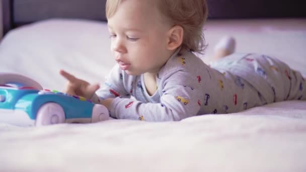 Infancia, ocio, juego, auto-aislamiento, tecnología, concepto de comunicación alegre lindo niño de dos años de pelo justo hablando en un teléfono de juguete y sonriendo . — Vídeo de stock