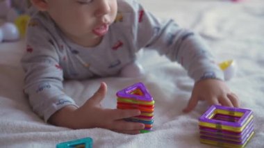 Çocukluk, eğlence, oyun, kendini izole etme, teknoloji, iletişim konsepti - neşeli, iki yaşındaki sarışın çocuk midenin üzerinde yatarken müteahhit tarafından oynanıyor..