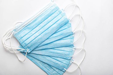 Birkaç tıbbi mavi kullan-at koruyucu maske üst üste beyaz arka planda vantilatör şeklinde. Cerrahi giysi ağız ve burnu kapatır. Sağlık, ilaç, covid-19, salgın konsepti..