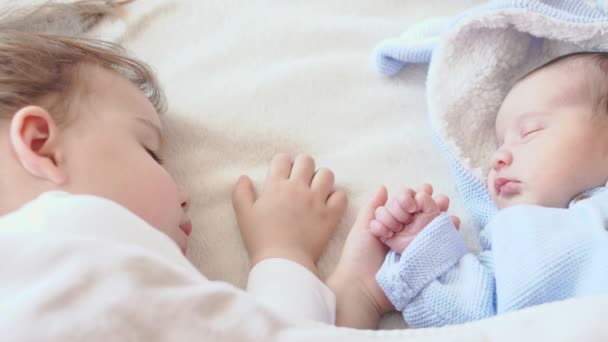 Infância, infância, família, sono, conceito de descanso - close-up de duas crianças, bebê recém-nascido e menina de três anos dormindo juntos em uma cama bege e branca. Irmãs estão dormindo no sofá em casa . — Vídeo de Stock